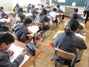 教卓の前に先生が立ち、席に座り授業をしている様子を教室の後ろから写した写真