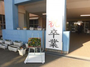 祝卒業と書かれた立て看板に太陽の光が反射し光っている写真