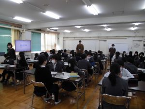 教室に複数の横長の机が置かれ、向かい合いに座り話している様子の写真