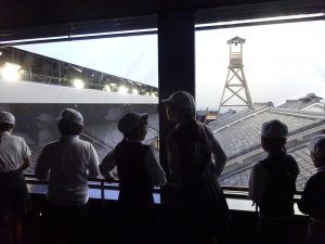 ガラスの向こうに展示されている建物を熱心に観察をしている生徒たちの写真