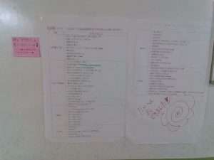 白い壁に貼られた、左横にピンク色の付箋と、白いプリントの右下に大きなはなまるが描かれた写真