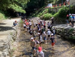 浅い川にたくさんの子どもたちが入り、遊んでいる様子の写真