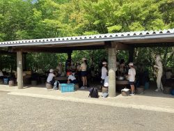 屋根のついた開放感ある炊事棟で、子どもたちがテーブルごとに集まっている写真