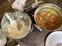 大きい鍋が並んで置かれ、鍋の中には白ご飯とカレーがそれぞれ少しずつ入っている写真