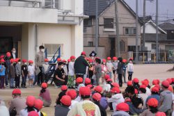 横一列に並んで立っている子どもたちの前に、先生や数名の子どもが集まっている写真