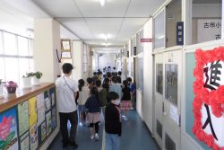 ポスターや植木鉢、赤色のお花紙で飾り付けられた廊下を向こう側へ歩いていく子どもたちの写真