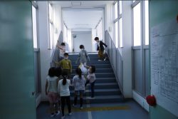 階段を下りてくる子どもたちと、階段下の廊下で待っている様子の子どもたちの写真