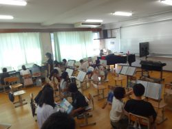 グランドピアノが置かれた部屋で、子どもたちが譜面台の前に座っている写真