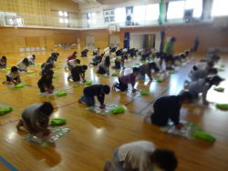 体育館にたくさんの子どもたちが集まり、両手を使って心臓マッサージの練習をしている写真