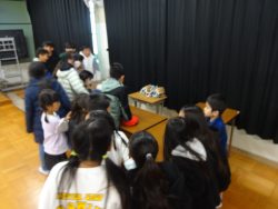 グローブが置かれた机の周りにたくさんの子どもたちが集まって眺めている写真
