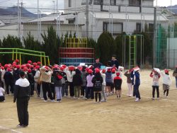 校庭にたくさんの子どもたちが整列しており、先生の方を向いている写真