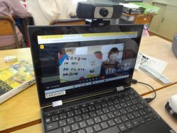 机の上に置かれたタブレットの画面に資料を発表している子どもたちが映っている写真