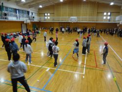 体育館内に帽子を被った子どもたちと大人の方が、それぞれコート内に集まって向き合っている写真