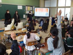 資料が映し出されたモニターと、椅子に着席して手を挙げている子どもたちの写真