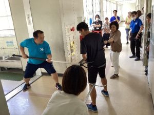 校内の廊下で不審者役の方を中心に、さすまたで両側から押さえる女性2人と前方から押さえる男性の訓練の写真