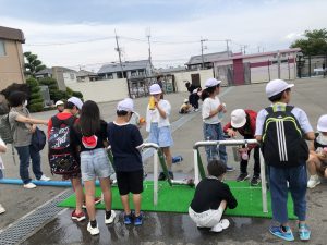 綺麗になった水が出てくる配管の前に子どもたちが集まり、水筒に水を入れている様子を写した写真