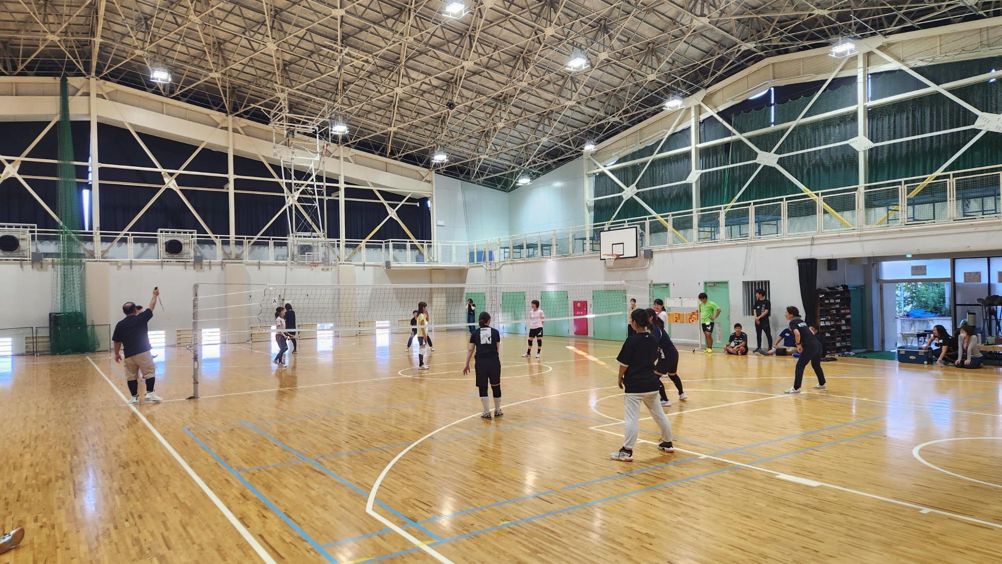 ネットが貼られた体育館内でソフトバレーボール大会が行われている様子の写真