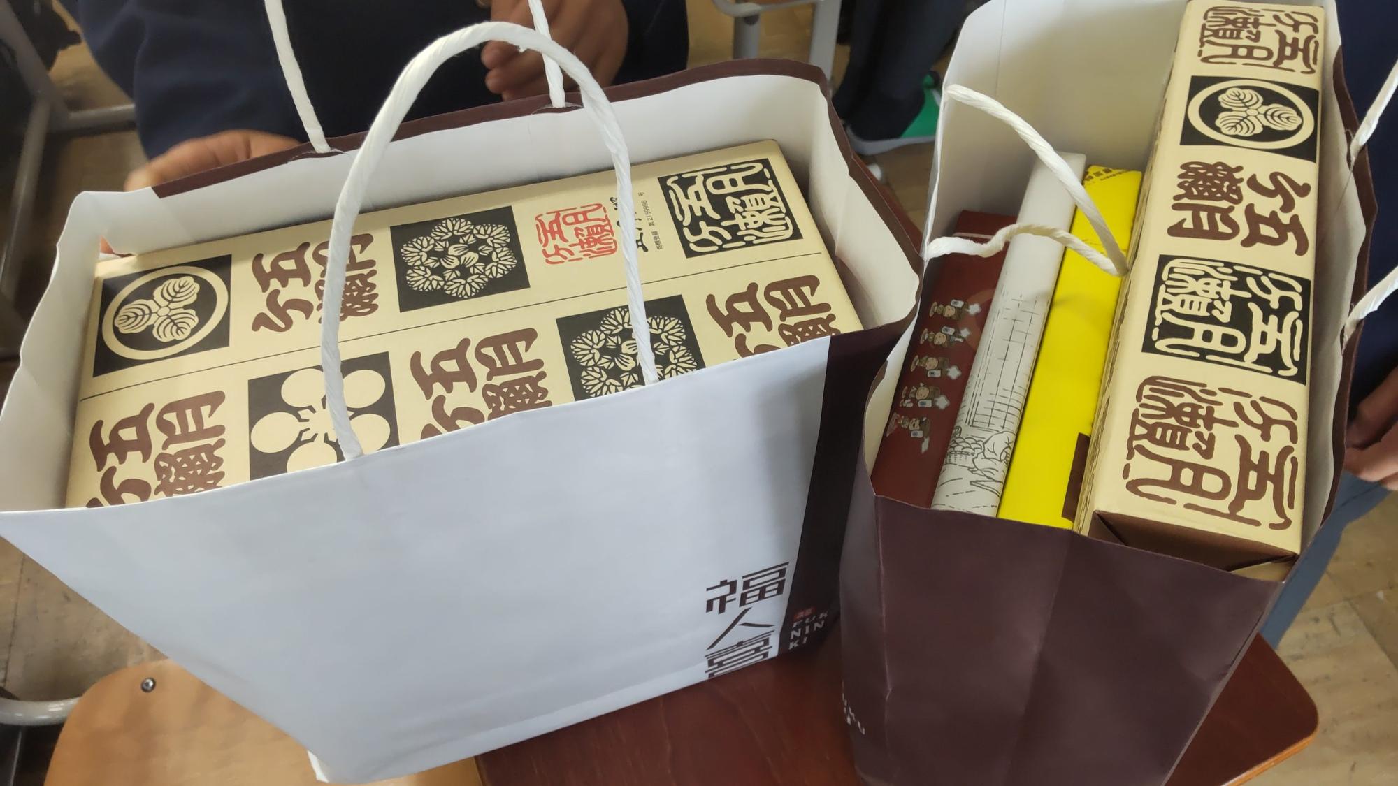 同じ包装紙でくるまれたお土産の箱が2つ入った左側の紙袋と、4種類の包装紙にくるまれたお土産が入った右側の紙袋が並んでいる写真