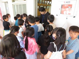 校長室の前に1年生の子どもたちが集まっており、校長先生が子どもたちを出迎えている様子の写真