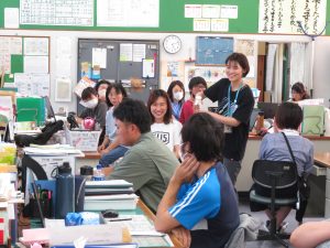 職員室に先生方が集まって座っており、和やかな雰囲気の中で職員会議が行われている様子の写真