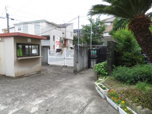 校門近くに管理等があり、校門の白い扉は閉められている様子を写した写真