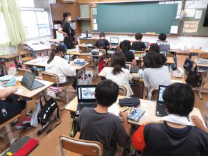 教室で子ども子ども達が席について、机の上にタブレットを広げ、画像を見ながらイラストを描いているイラストクラブ活動の様子の写真