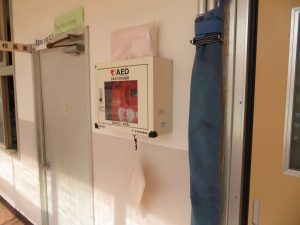 校長室横の壁に設置されている「AED」と「担架」の写真