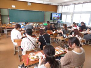 参加者の方々が席に着き、給食を食べている様子を後方より写した写真