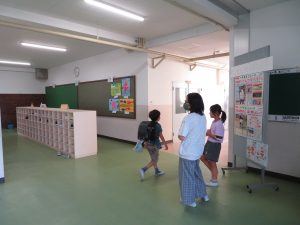 児童下足に2名の女子生徒が立ち、登校してくる児童に挨拶をしている様子の写真