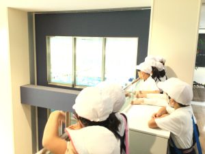 手すりの手前側に立っている子どもたちが、覗き込むような様子で見学をしている写真