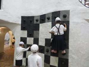 黒やグレーで模様が描かれた壁に突起物がついており、生徒たちが壁上りをしている写真