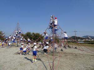 公園にあるロープが張り巡らされた塔のような遊具に子どもたちが登って遊んでいる様子の写真