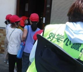 勝手口と書かれた玄関の前に数名の児童と保護者の方が立っている写真